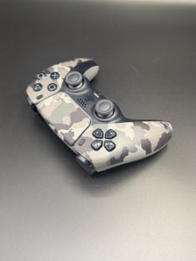 Right-front angled view of Gray Camouflage PS5 DualSense unit PS5-CMO-002 showing the face buttons and right grip